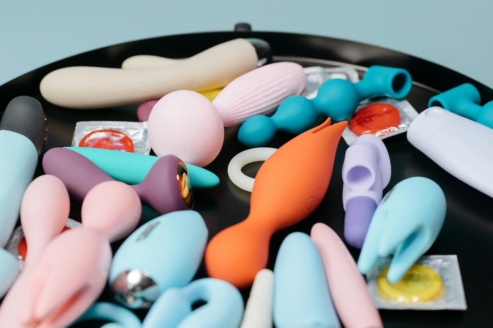 A vibrant collection of various sex toys on a black tray, featuring diverse shapes and colors.